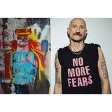 Mężczyzna w czarnej koszulce z napisem 'NO MORE FEARS', obok kolorowego graffiti, styl uliczny, moda z kulturą
