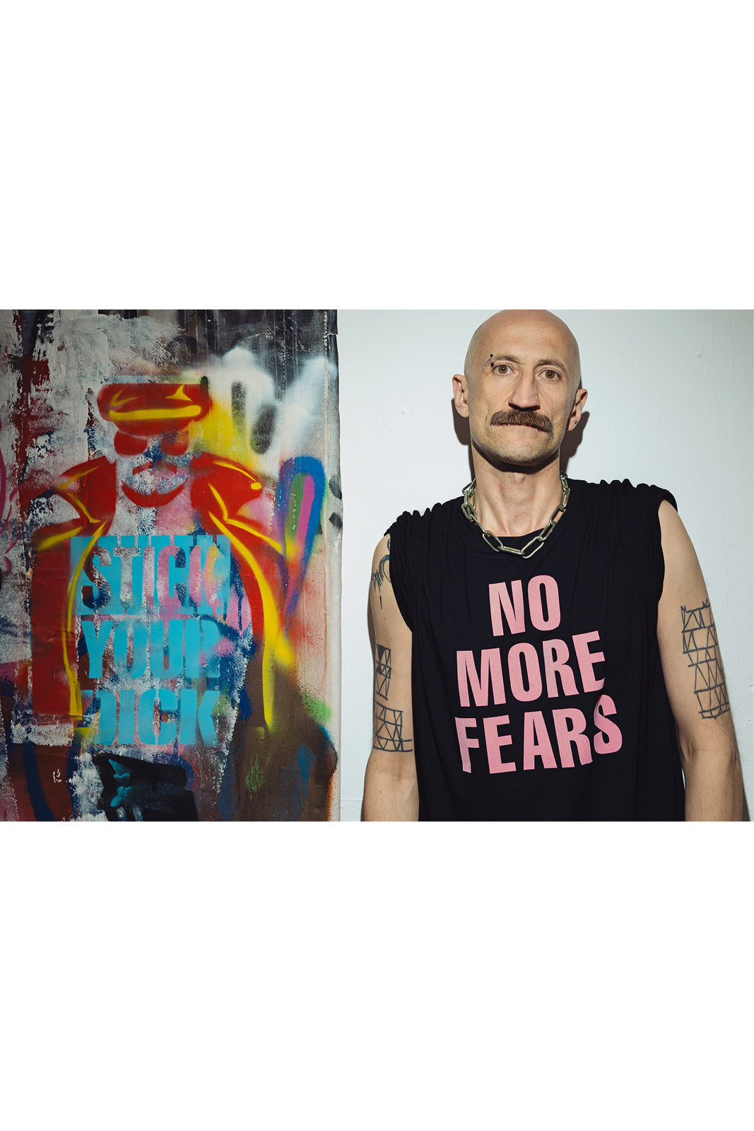 Mężczyzna w czarnej koszulce z napisem 'NO MORE FEARS', obok kolorowego graffiti, styl uliczny, moda z kulturą