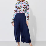 Kobieta w kolorowej bluzce z kwiatowym wzorem i granatowych spodniach culottes, stylowa moda damska