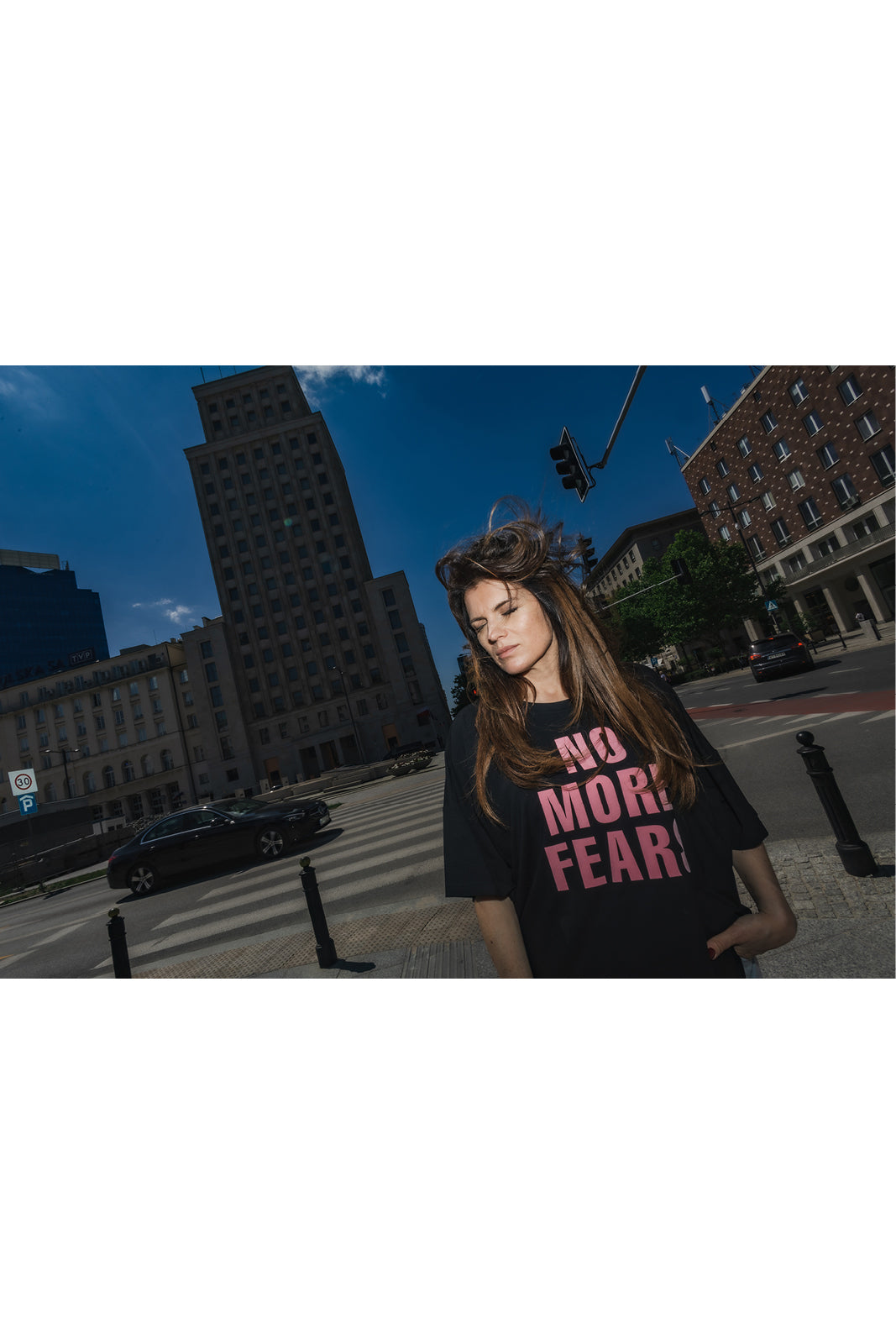Czarna koszulka z napisem NO MORE FEAR, stylowa moda miejska na tle Warszawy, self-care fashion