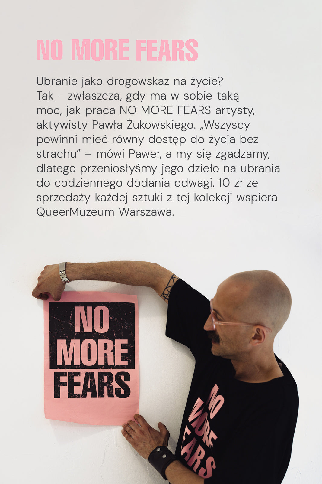 Mężczyzna w czarnej koszulce z napisem NO MORE FEARS trzyma plakat z tym samym hasłem – moda z misją, wspierająca QueerMuzeum Warszawa.