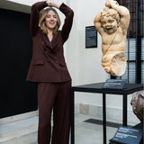 Kobieta w brązowym garniturze z rzeźbą w tle, stylowa i wygodna moda polska