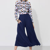 Kobieta w kolorowej koszuli w kwiaty i granatowych spodniach typu culottes, stylowa moda damska