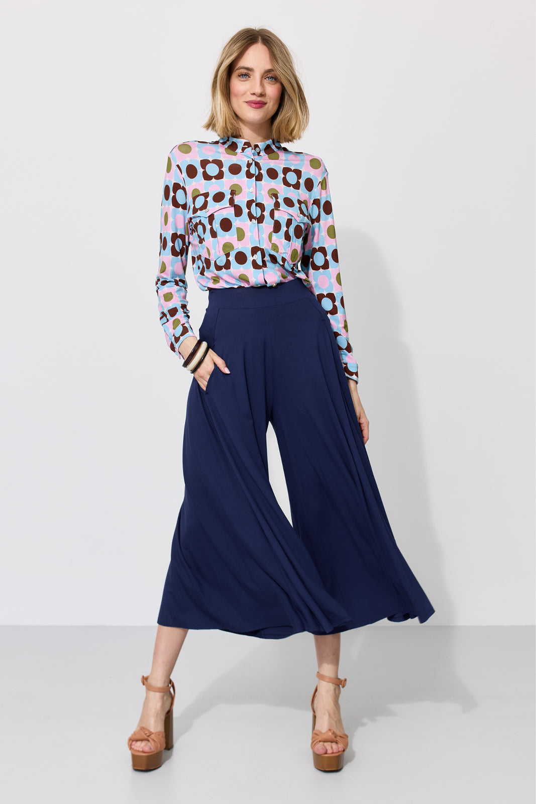 Kobieta w kolorowej koszuli w kwiaty i granatowych spodniach typu culottes, stylowa moda damska