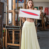 Kobieta w żółtej sukience trzyma obraz w artystycznym atelier