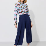 Kobieta w kolorowej bluzce z kwiatowym wzorem i granatowych spodniach culottes, stylowa moda damska