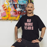 Mężczyzna w czarnej koszulce z napisem 'NO MORE FEARS' przed kolorowym graffiti, styl uliczny, moda z kulturą