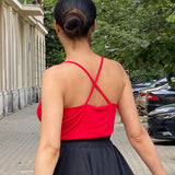 Czerwony top z krzyżowanymi ramiączkami i czarna spódnica w stylu self-care fashion, idealny na codzienne stylizacje.