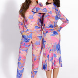 Kobiety w kolorowych, abstrakcyjnych strojach – bluza i spodnie oraz sukienka z falebkami, styl self-care fashion