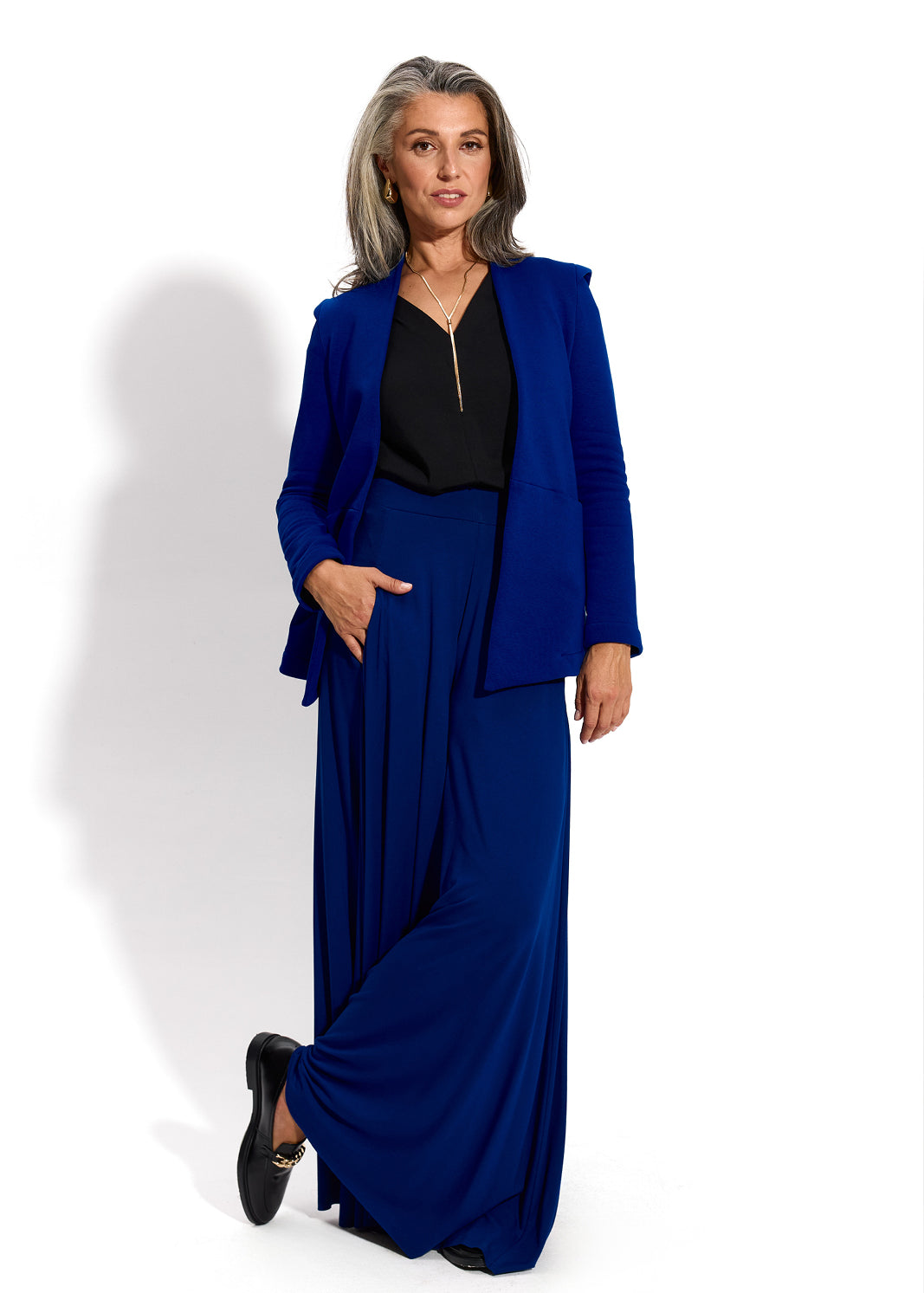 Elegancka kobieta w granatowym garniturze z długimi spodniami i czarną bluzką, stylowa moda damska
