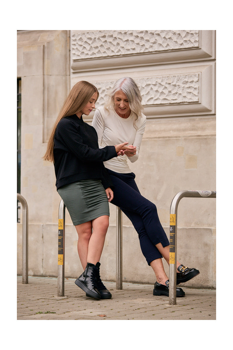 Kobiety w eleganckich ubraniach codziennych – zielona spódnica, czarne buty, biała bluzka – stylowy streetwear